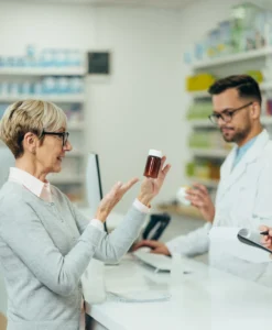 Woman holding medication, asking pharmacist if she can get a repeat prescription